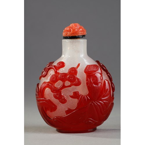 Snuff bottle  red overlay glass with Shou Lao holding a peche of longevity and looking at peches and on the other side of a character holding a cup on a tray in front of a pine - China 1800/1850